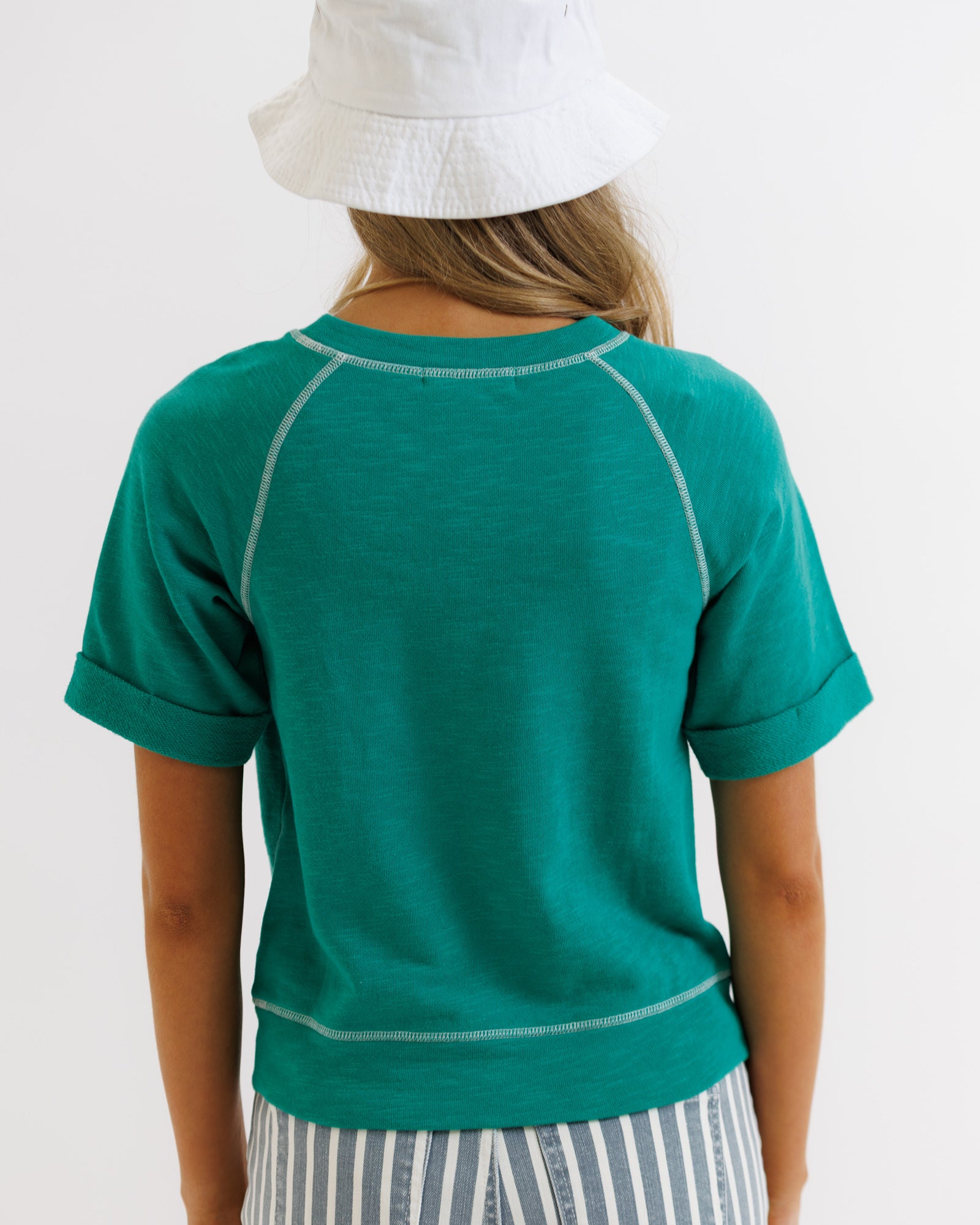 Person wearing a green shirt with white trim on a plain background