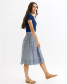 Woman wearing a blue top and checkered skirt on a white background