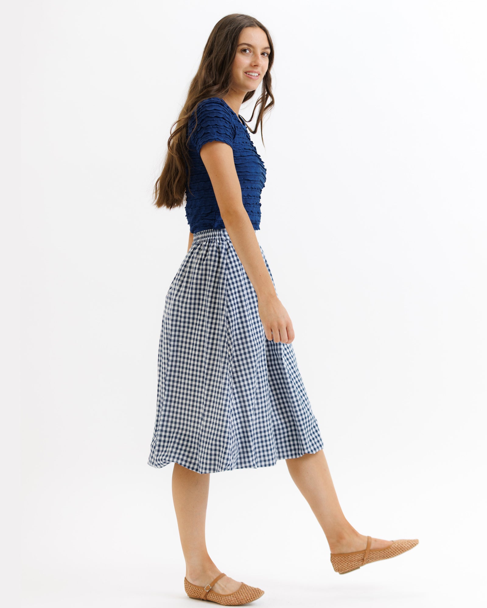 Woman wearing a blue top and checkered skirt on a white background