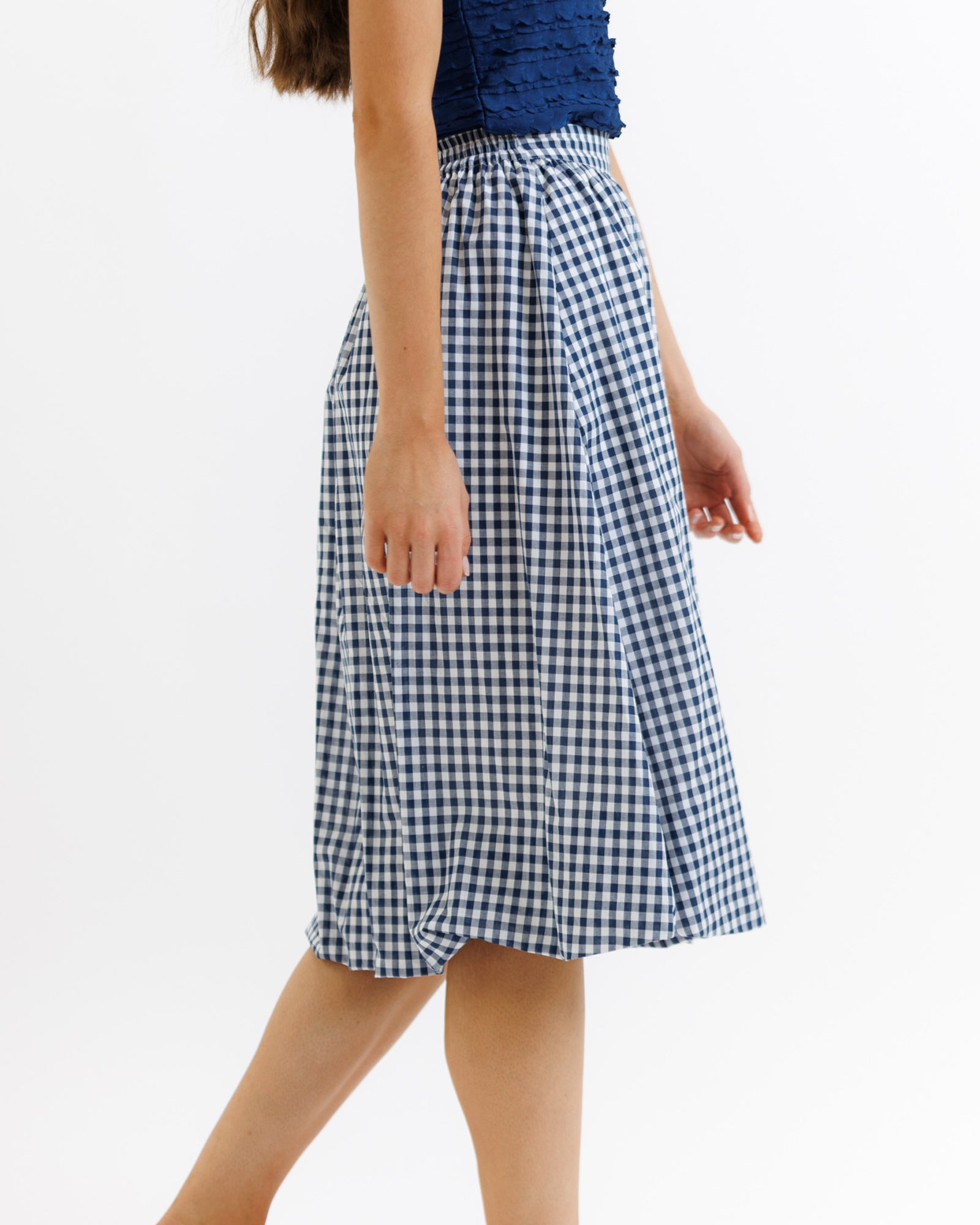 Person wearing a blue and white checkered skirt on a white background