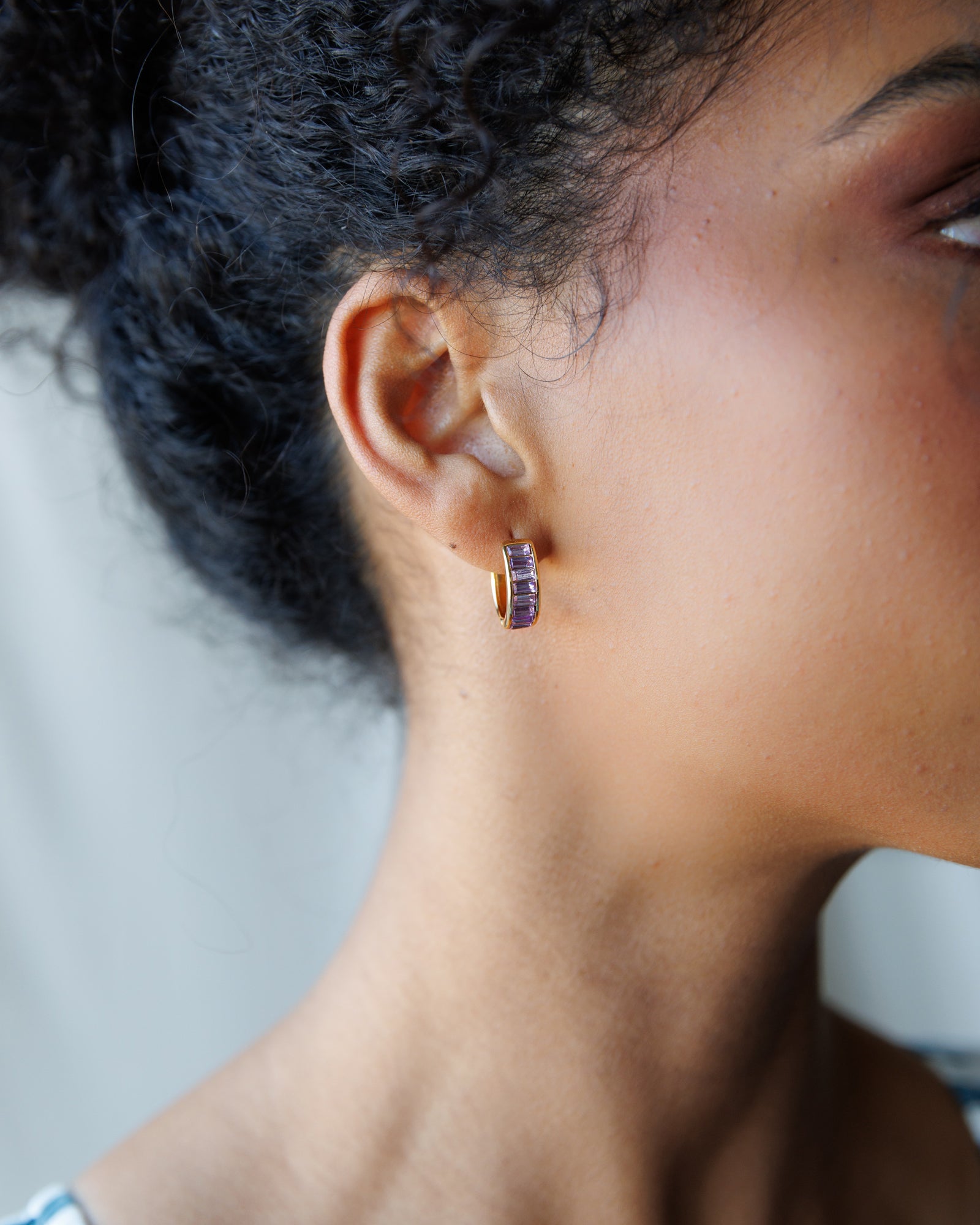 Close-up of a person wearing a hoop earring with a blurred background