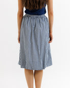 Person wearing a blue and white checkered skirt on a white background