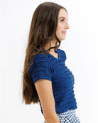 Woman wearing a blue textured top with a white background