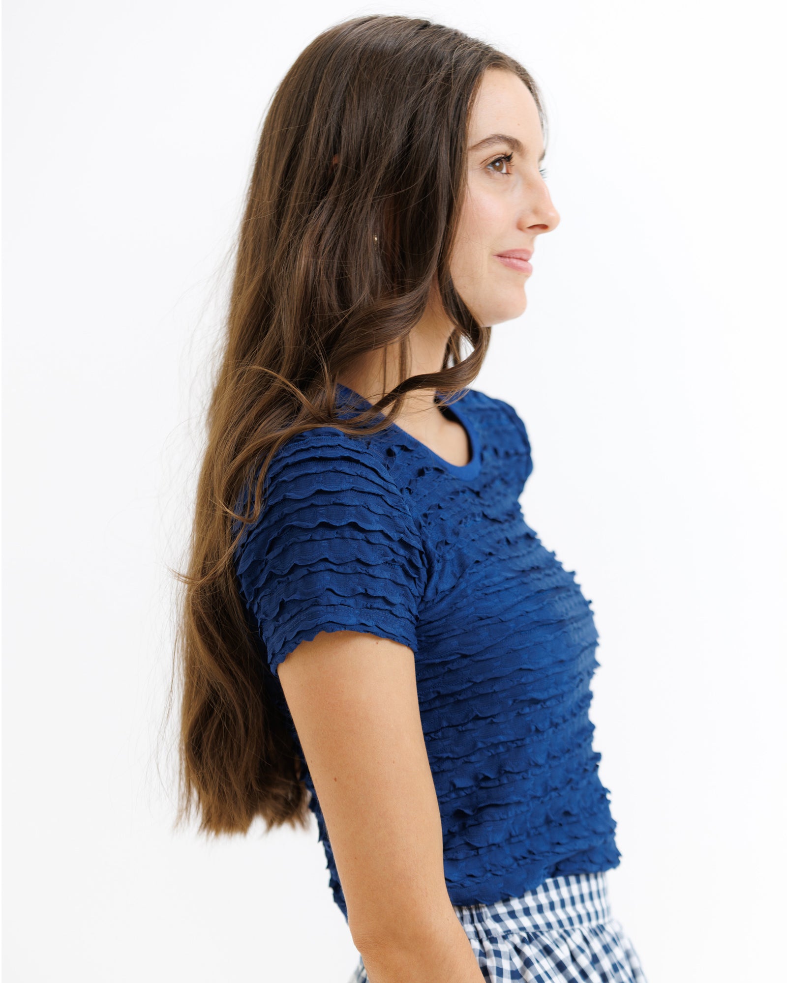 Woman wearing a blue textured top with a white background