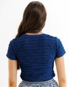 Woman wearing a blue textured top on a white background