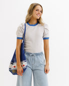 Woman wearing a striped shirt and holding a blue bag on a white background