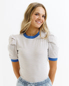Woman wearing a striped shirt with blue trim on a white background