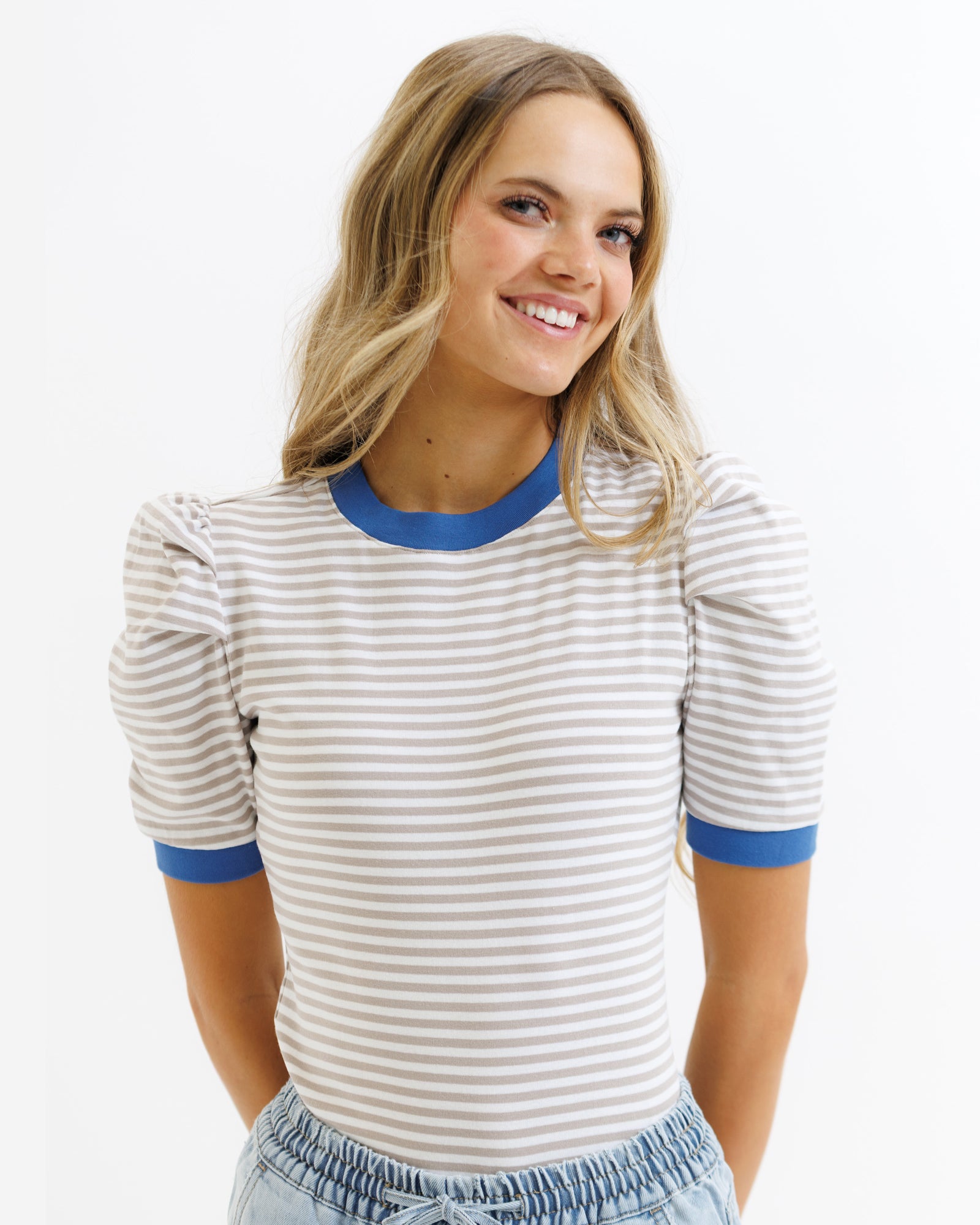 Woman wearing a striped shirt with blue trim on a white background