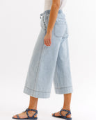 Light blue denim wide-leg pants worn by a person on a white background