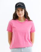 Woman wearing a pink t-shirt and black cap with 'Brooklyn' text on a white background