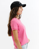 Woman wearing a black cap and pink shirt on a white background