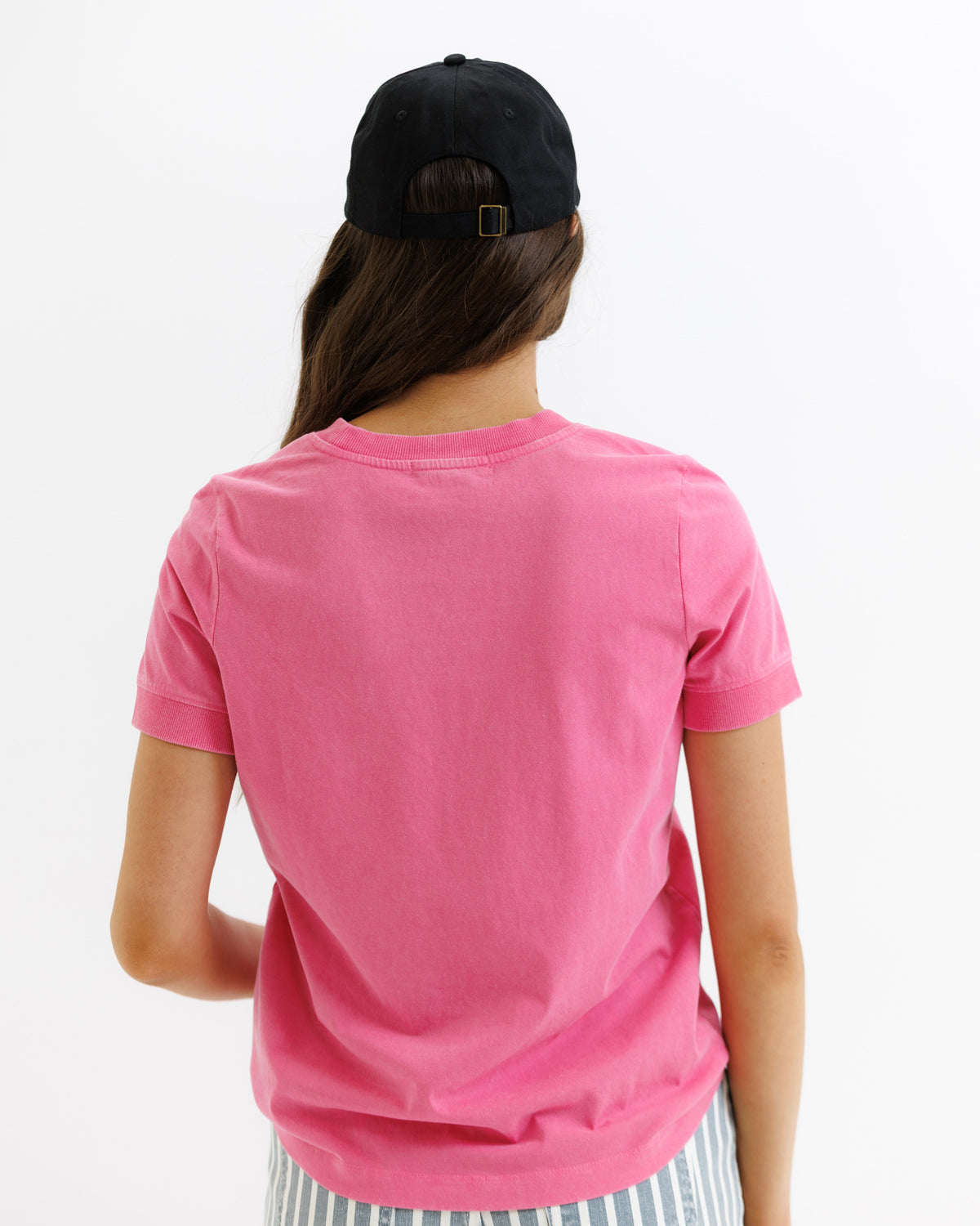 Person wearing a pink t-shirt and black cap from behind on a white background