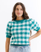 Woman wearing a green and white checkered shirt against a white background
