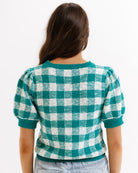 Person wearing a green and white checkered sweater on a white background