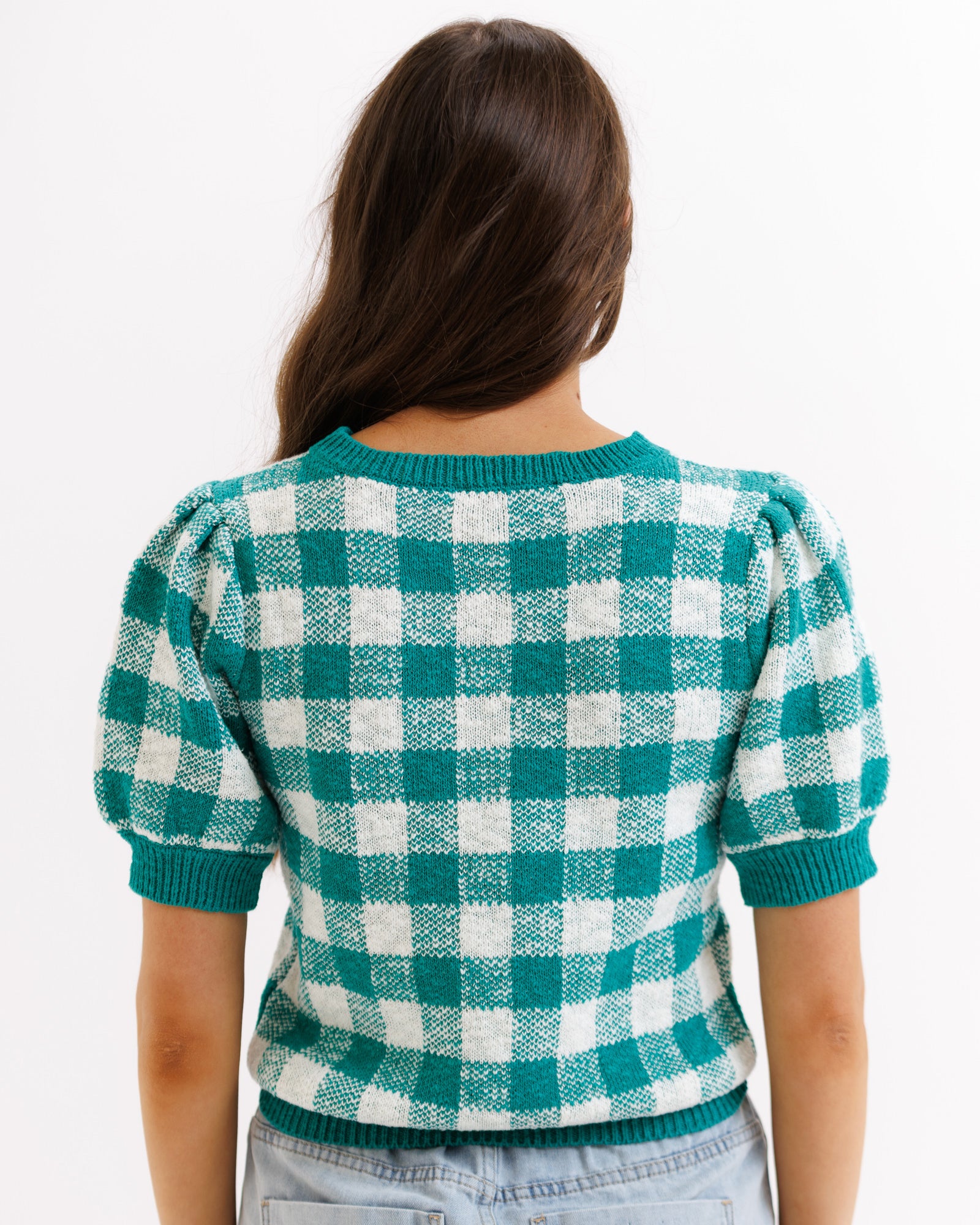 Person wearing a green and white checkered sweater on a white background