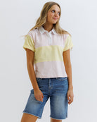 Woman wearing a two-tone polo shirt and denim shorts on a white background