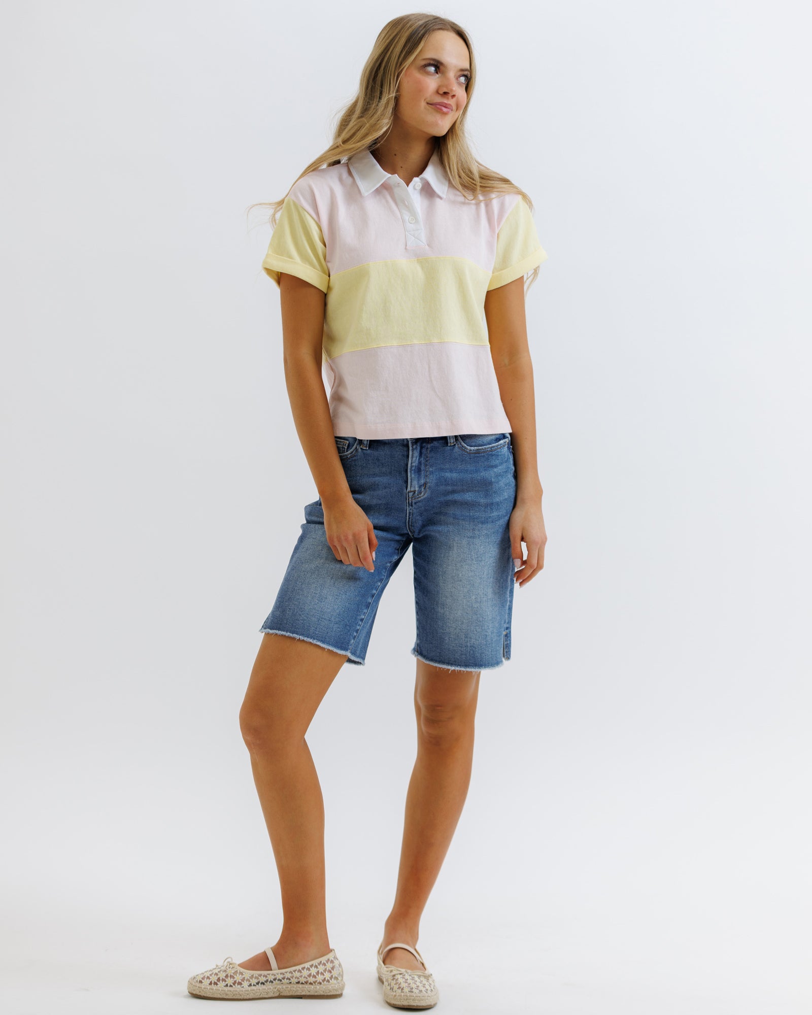 Woman wearing a striped shirt and denim shorts on a white background