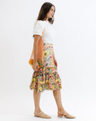 Woman wearing a floral skirt and white top with a white background