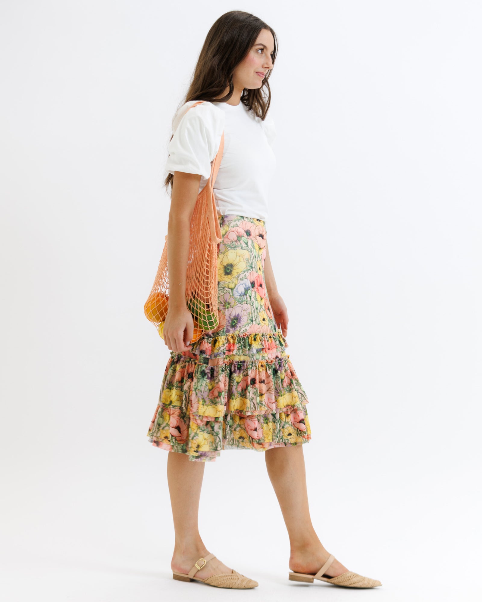 Woman wearing a floral skirt and white top with a white background