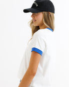 Woman wearing a white shirt with blue accents and a black cap on a white background