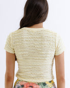 Person wearing a light-colored textured top with floral pants on a white background
