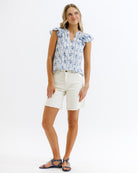 Woman wearing a floral top and white shorts on a white background