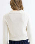 White ribbed knit cardigan worn by a person on a white background