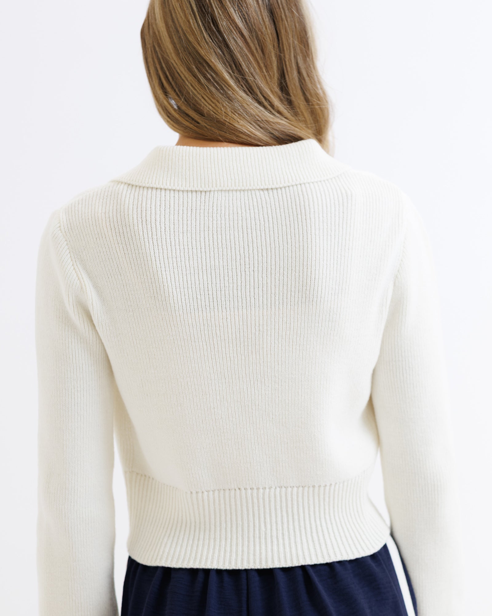 White ribbed knit cardigan worn by a person on a white background