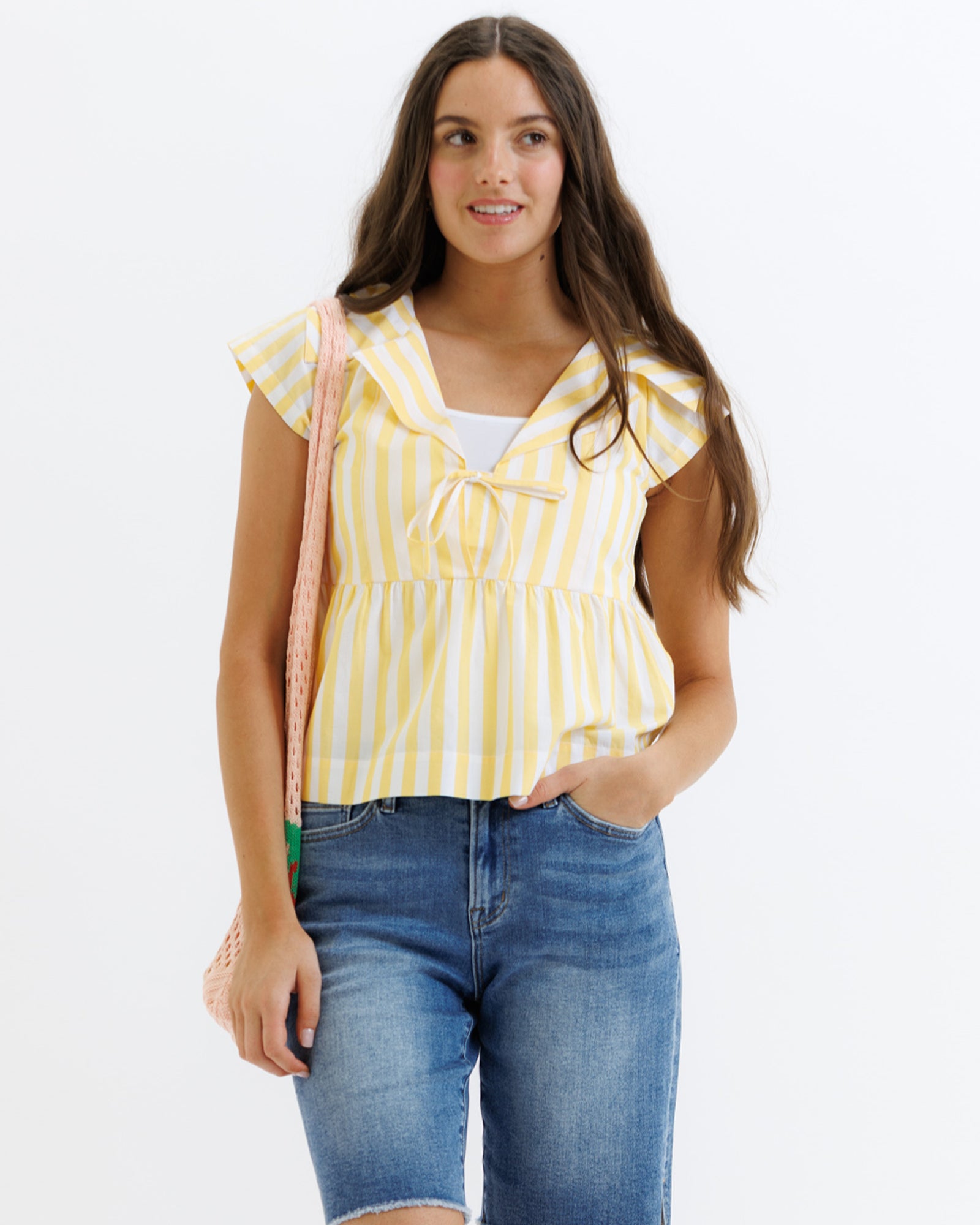 Woman wearing a yellow striped top and blue jeans on a white background