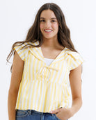 Woman wearing a yellow and white striped top on a white background