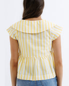 Yellow and white striped top worn by a person on a plain background