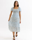 Woman wearing a light blue floral dress on a white background