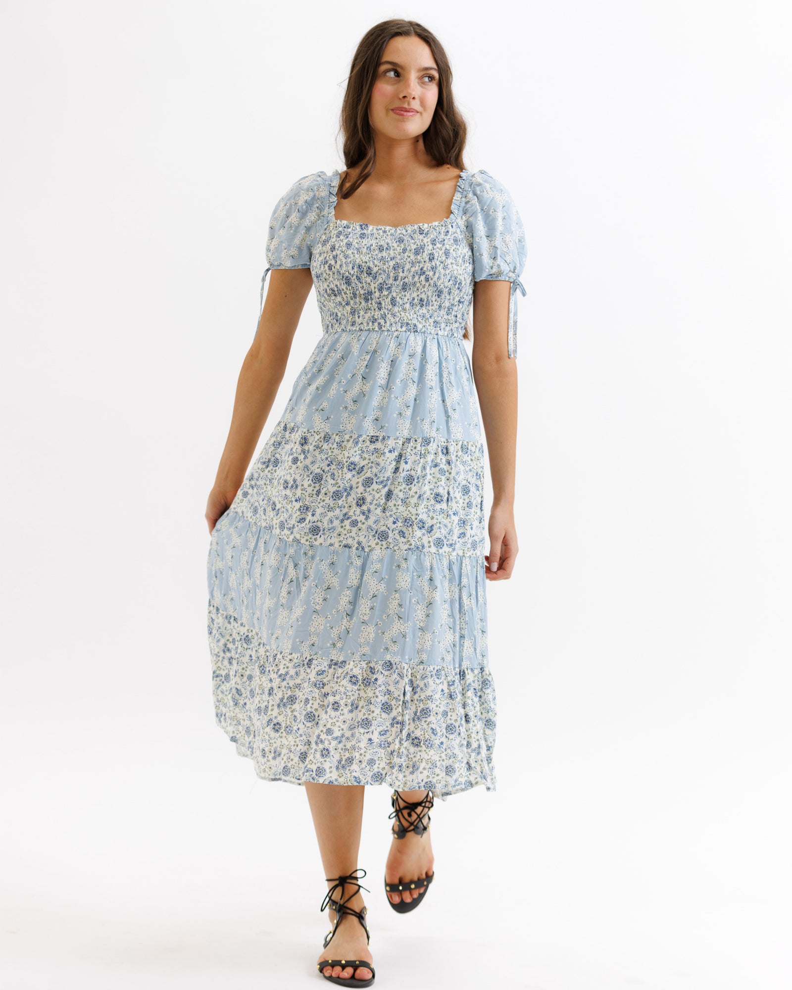 Woman wearing a light blue floral dress on a white background