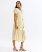 Woman wearing a yellow floral dress on a white background