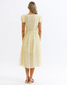 Woman wearing a yellow floral dress on a white background