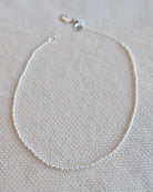 Silver necklace on a beige textured fabric background