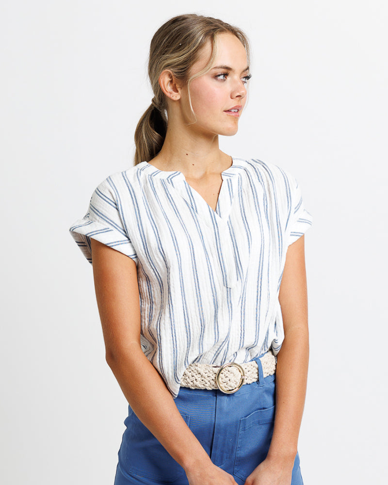 Model wearing a white and blue vertical striped short sleeve v-neck loose fitting blouse
