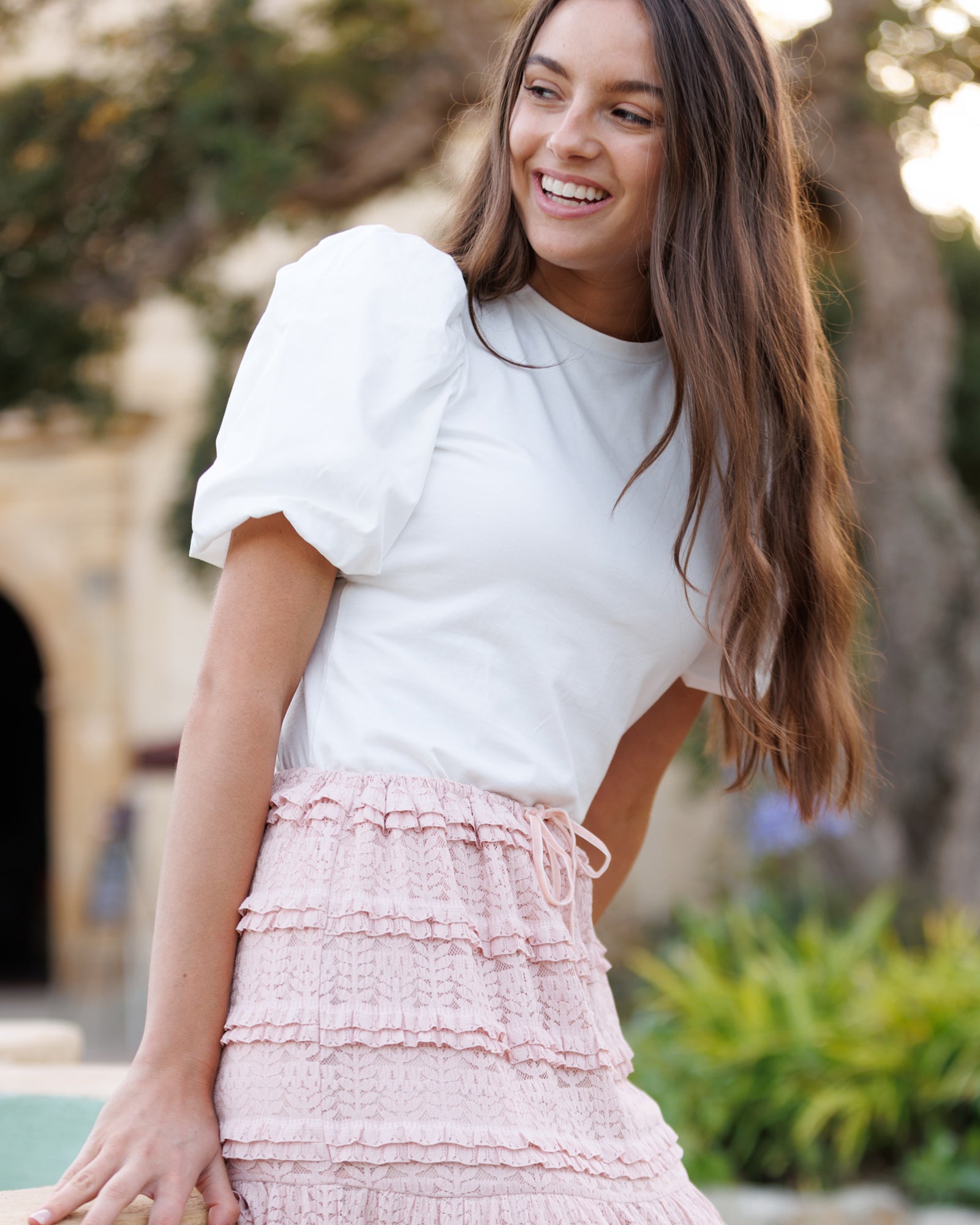 Woman wearing a white top and pink skirt outdoors