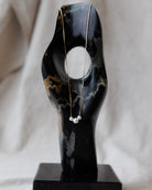 Black marble sculpture with a necklace on a neutral background