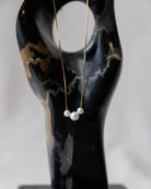 Pearl necklace on a black marble stand with a white background