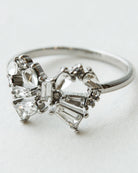 Silver ring with heart-shaped diamond design on a light gray background