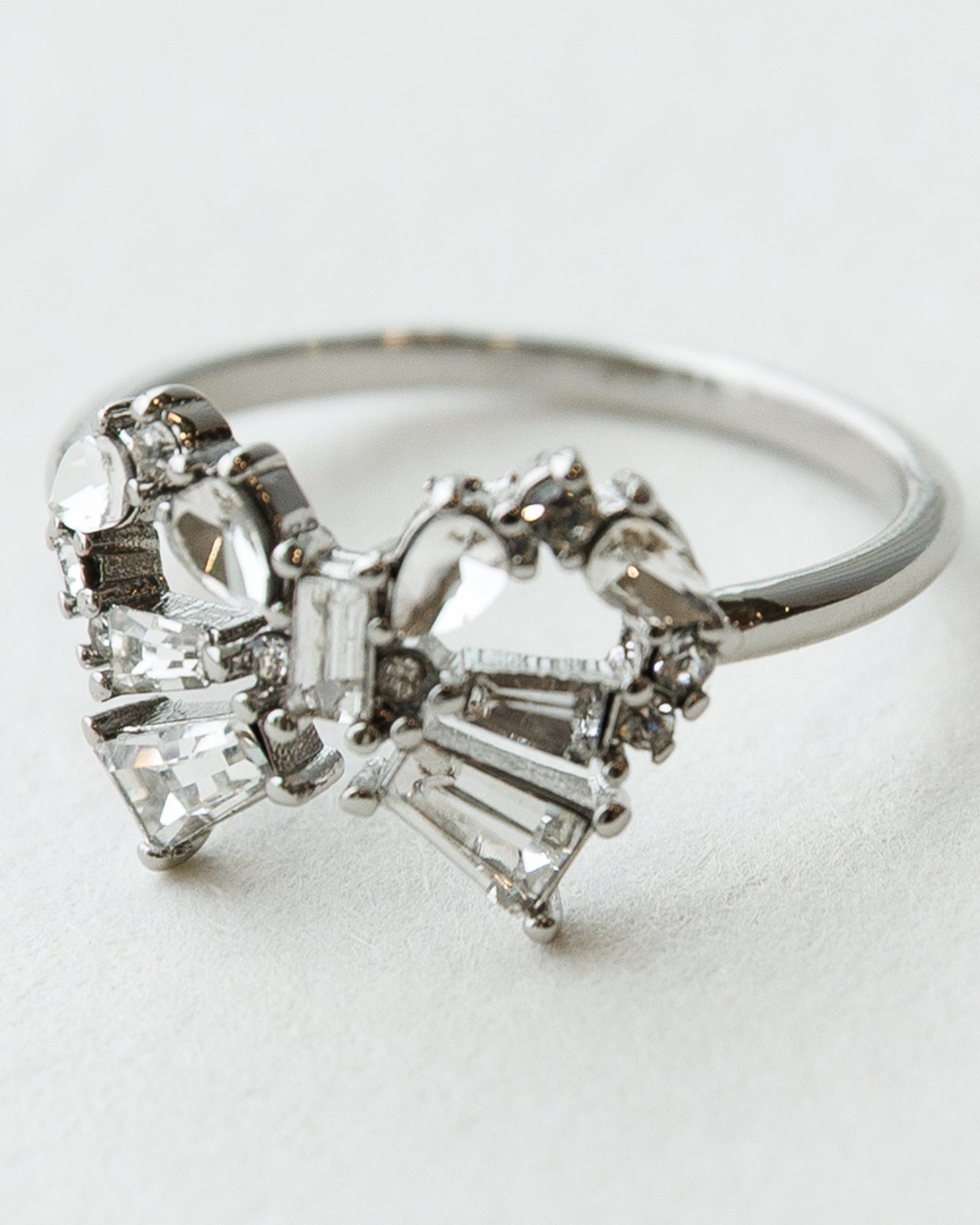 Silver ring with heart-shaped diamond design on a light gray background