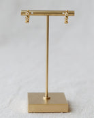 Gold earring stand with earrings on a light gray background
