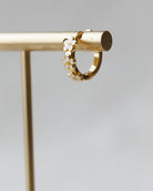 Gold hoop earring with floral details on a gray background