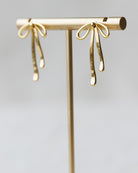 Gold earring on a stand with a plain background