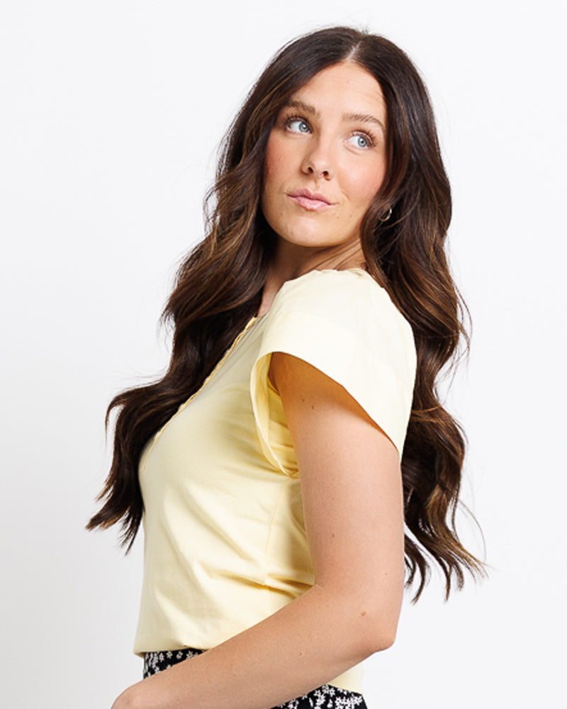Model wearing a yellow short flutter sleeve round neck henley top