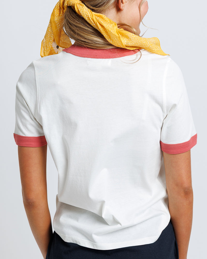 Model wearing a white short sleeve graphic t-shirt with orange trim