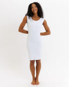 Woman wearing a white sleeveless dress on a plain background