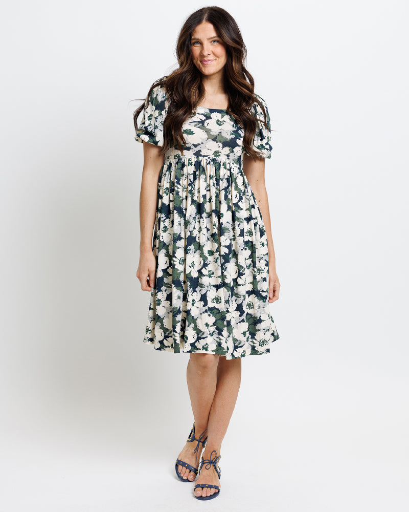 Model wearing a navy, green and white floral print short sleeve square neck knee length dress