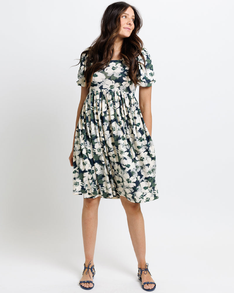 Model wearing a navy, green and white floral print short sleeve square neck knee length dress